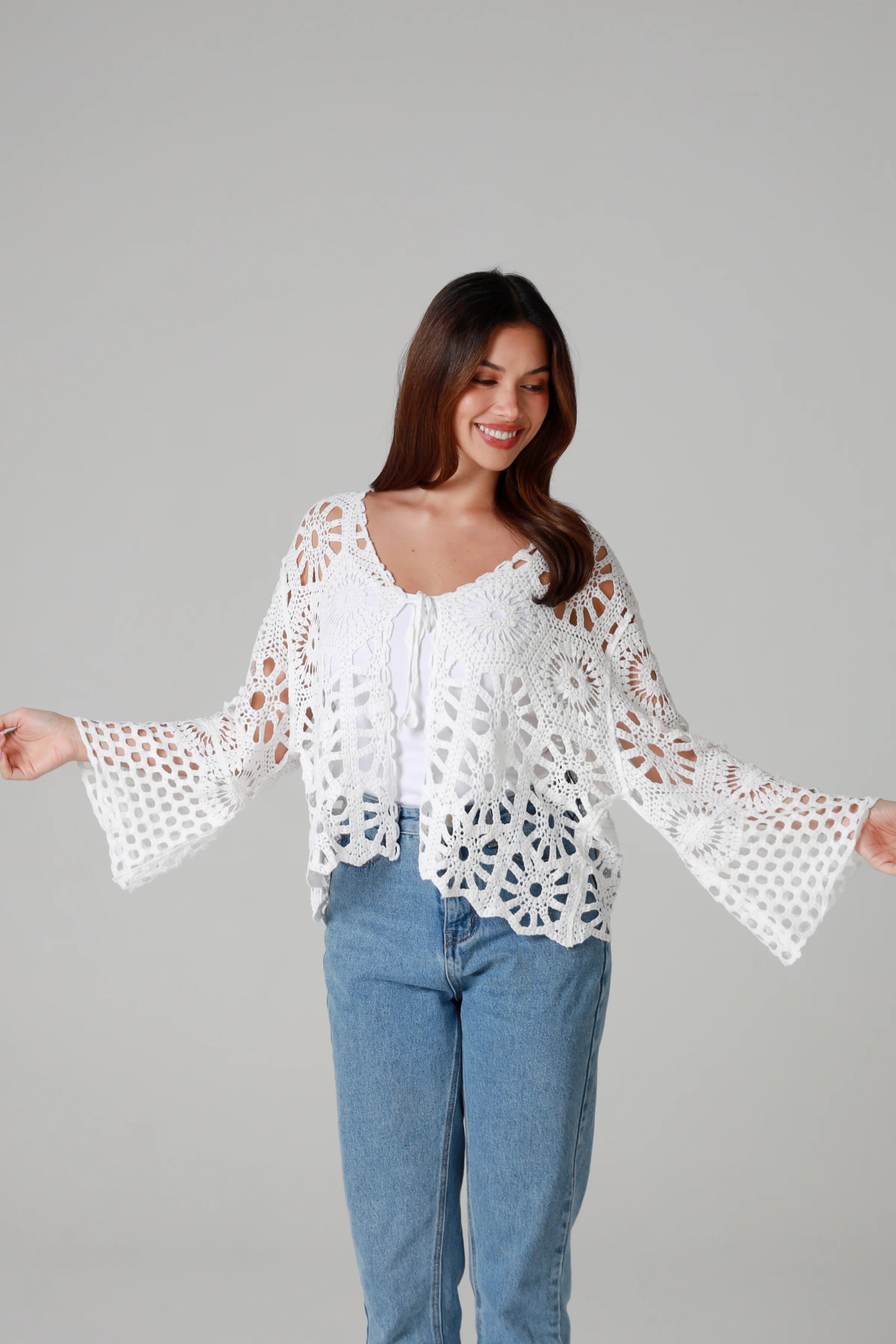 White crochet cardigan with tie front and boho bell sleeves layered over denim - crochet cardigan Australia.