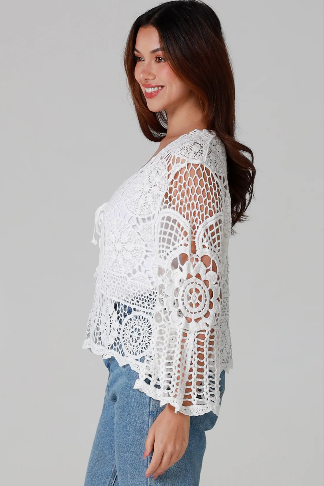 Woman in white cotton crochet embroidered top with flared sleeves and tie-front – Australian boho style