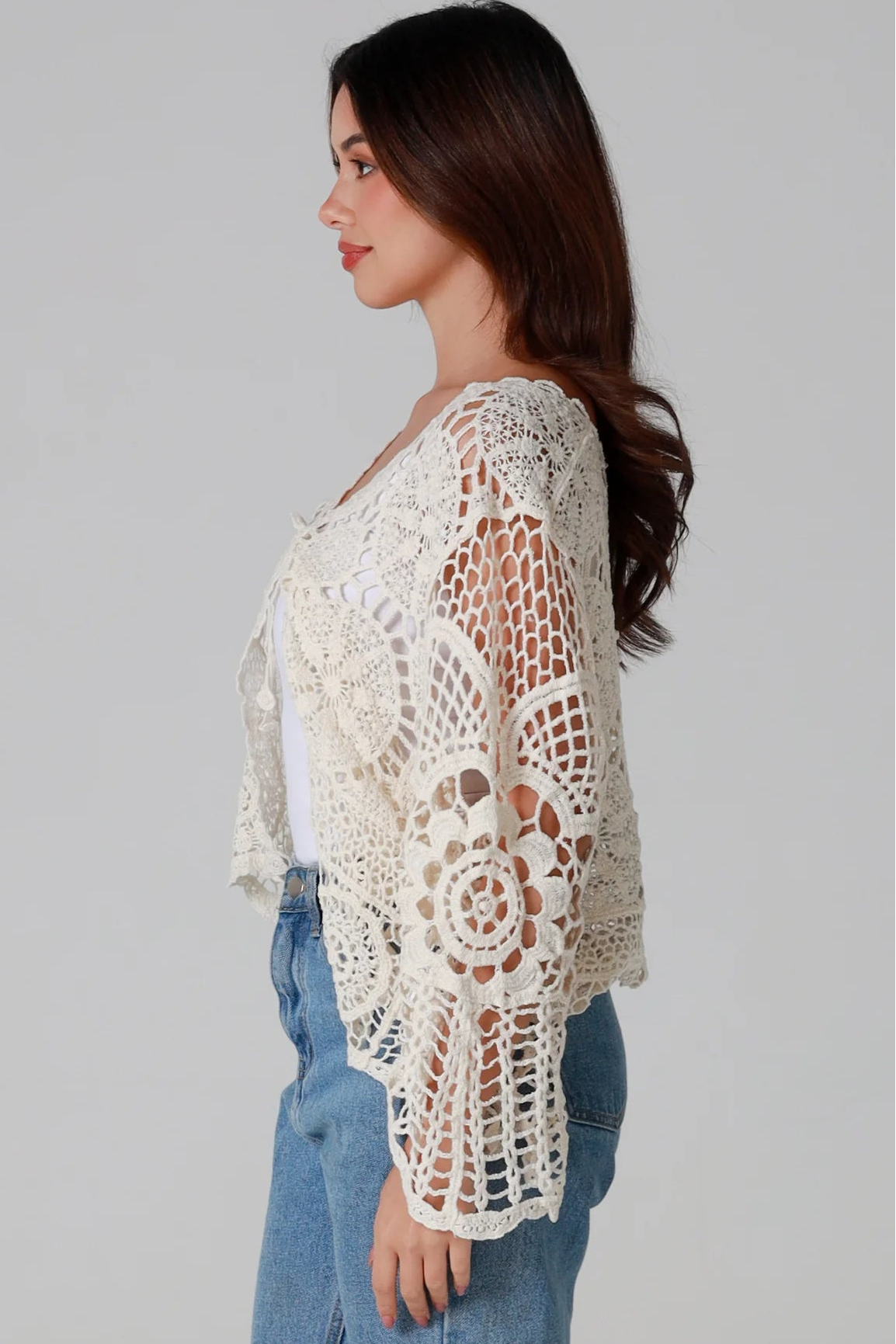 Woman in cream cotton crochet embroidered cardigan with flared sleeves and scalloped edges – Australian boho style