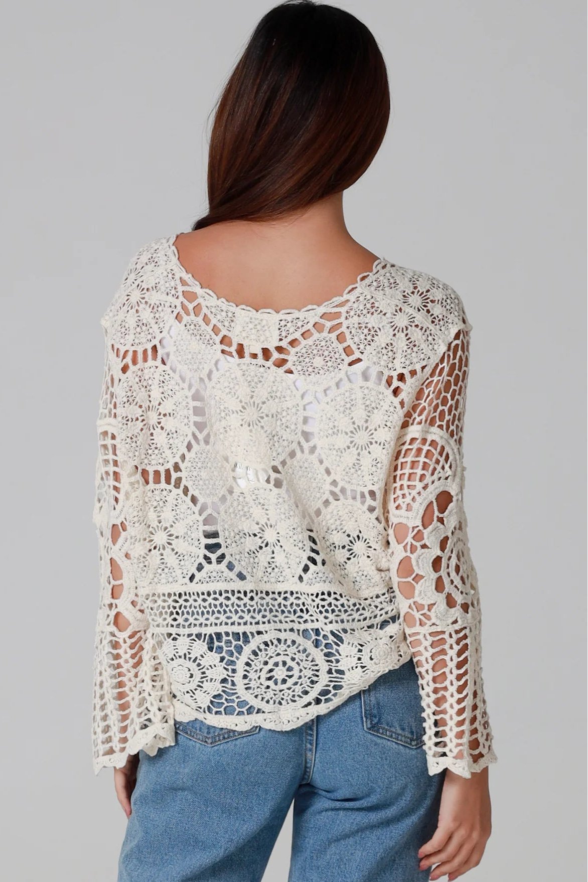Woman in cream cotton crochet embroidered cardigan with flared sleeves and scalloped edges – Australian boho style