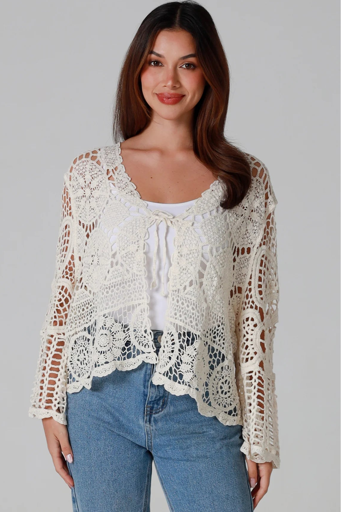 Woman in cream cotton crochet embroidered cardigan with flared sleeves and scalloped edges – Australian boho style