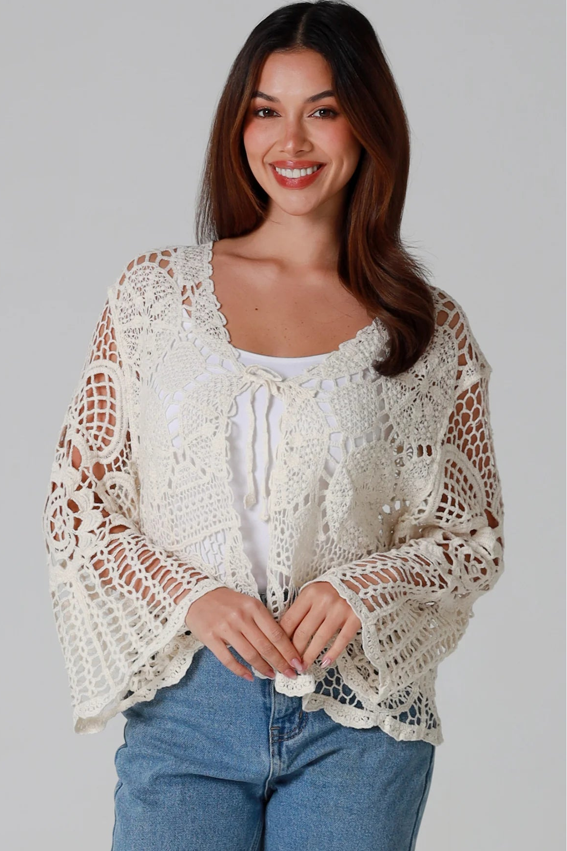 Woman in cream cotton crochet embroidered cardigan with flared sleeves and scalloped edges – Australian boho style