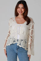 Woman in cream cotton crochet embroidered cardigan with flared sleeves and scalloped edges – Australian boho style