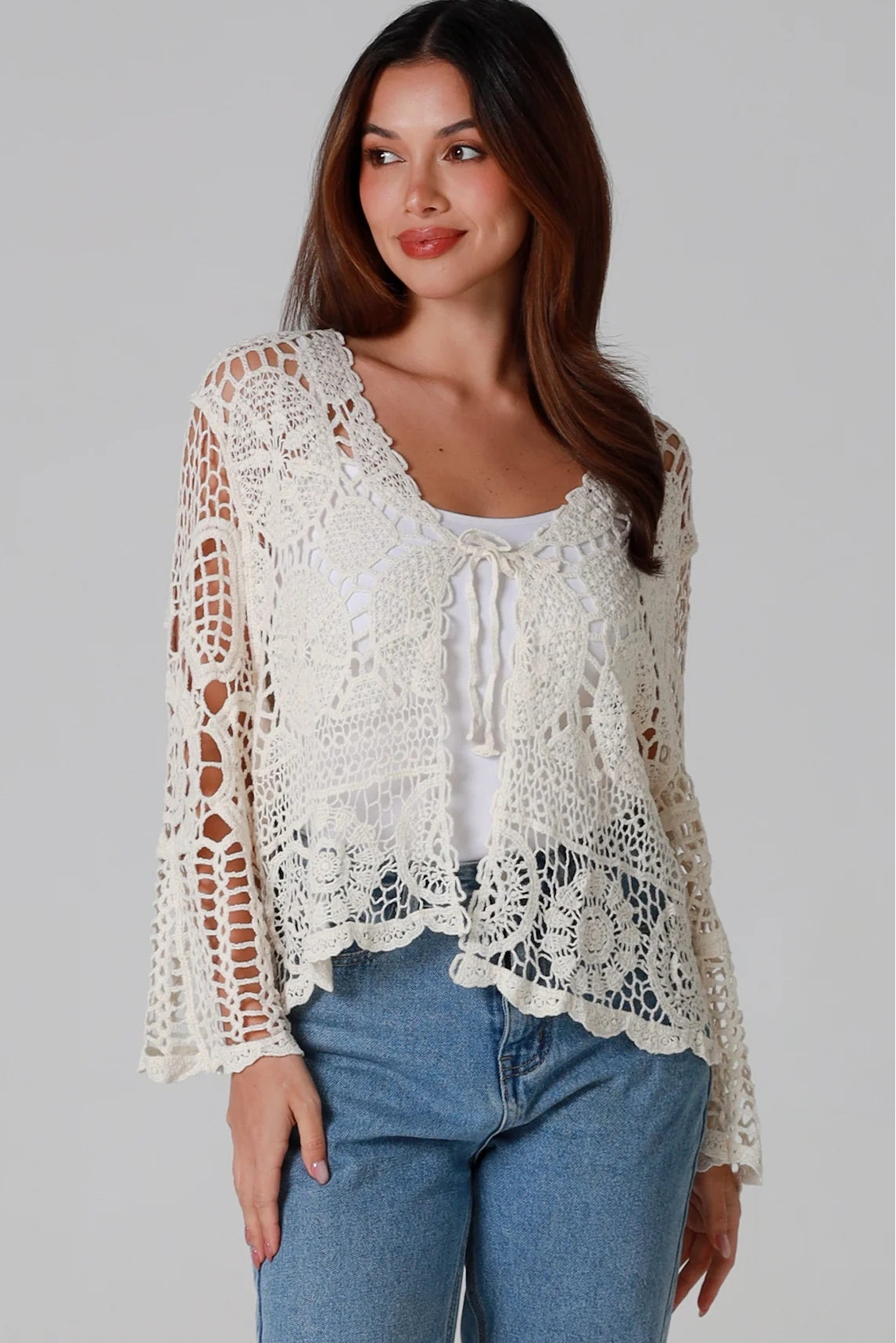 Woman in cream cotton crochet embroidered cardigan with flared sleeves and scalloped edges – Australian boho style