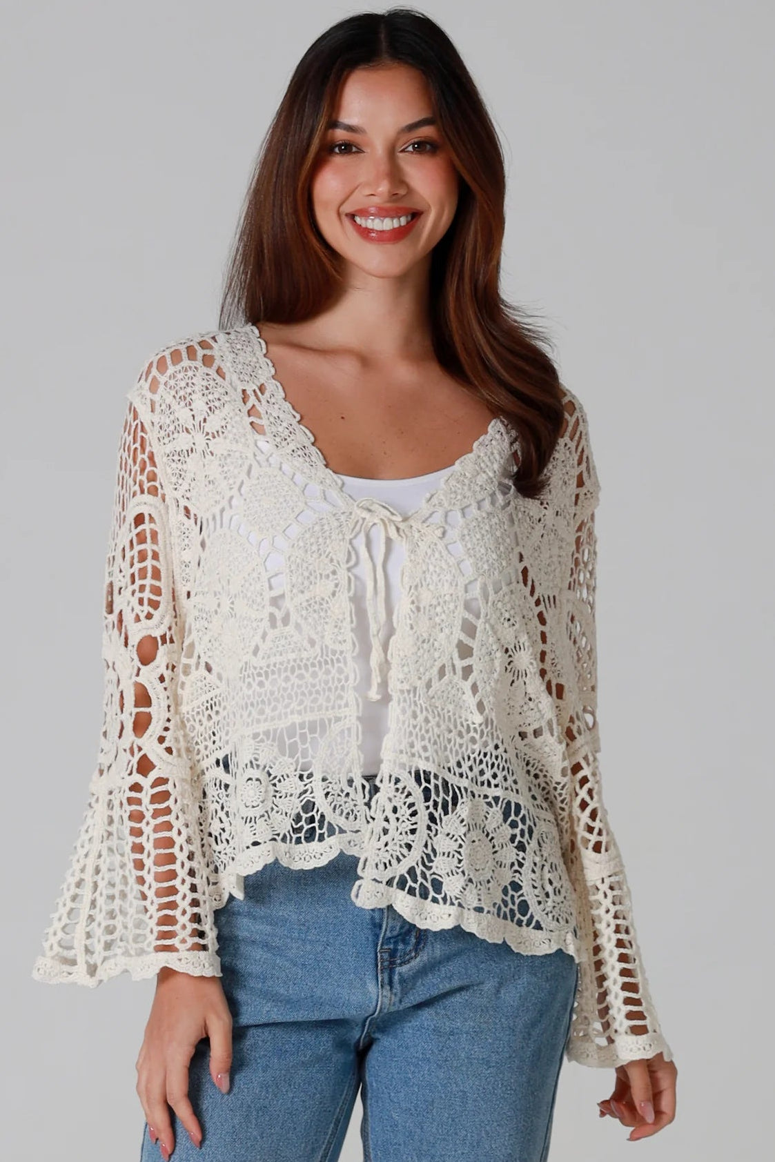 Woman in cream cotton crochet embroidered cardigan with flared sleeves and scalloped edges – Australian boho style