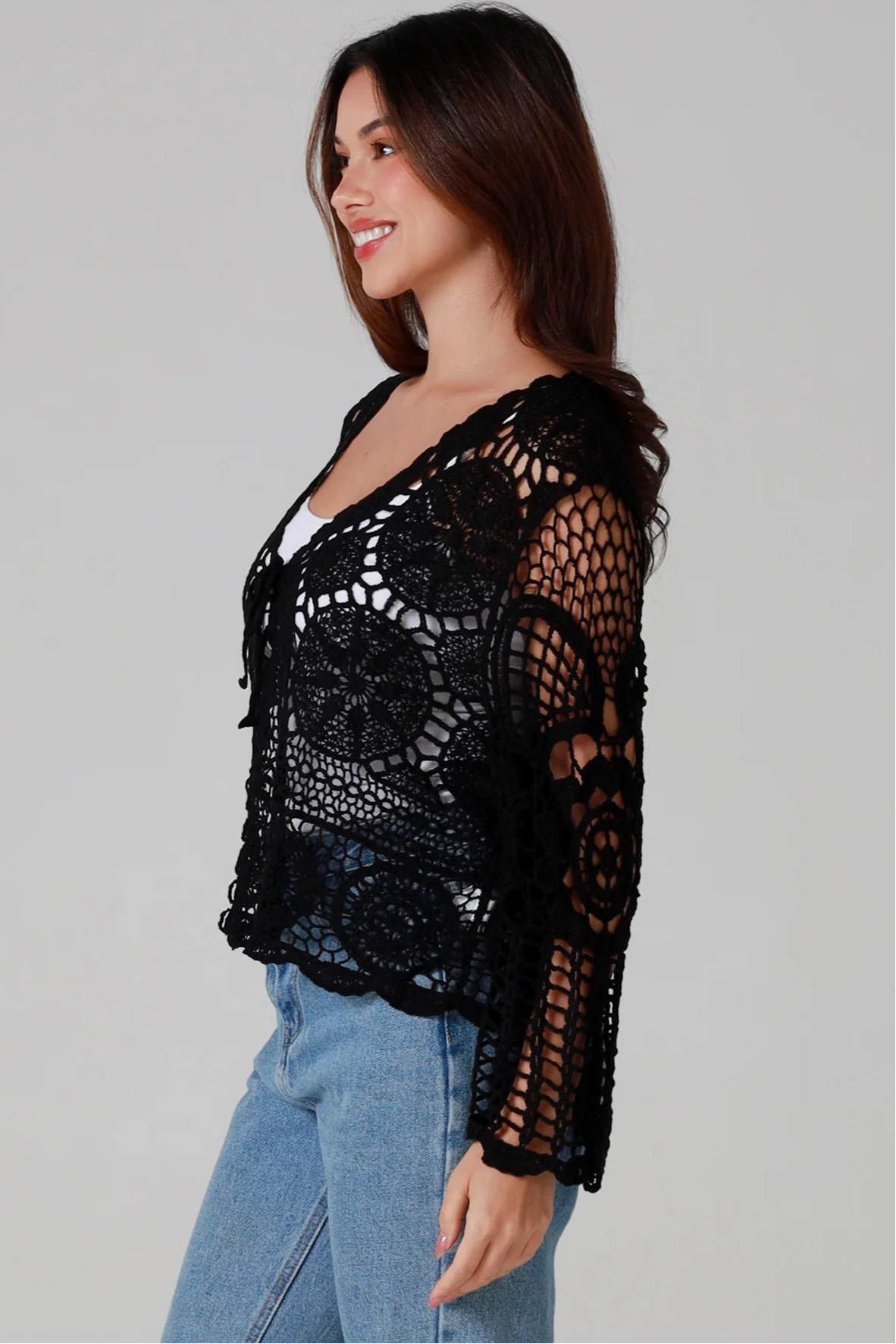 Woman in black 100% cotton crochet top with bell sleeves and tie front - one size boho top styled with denim
