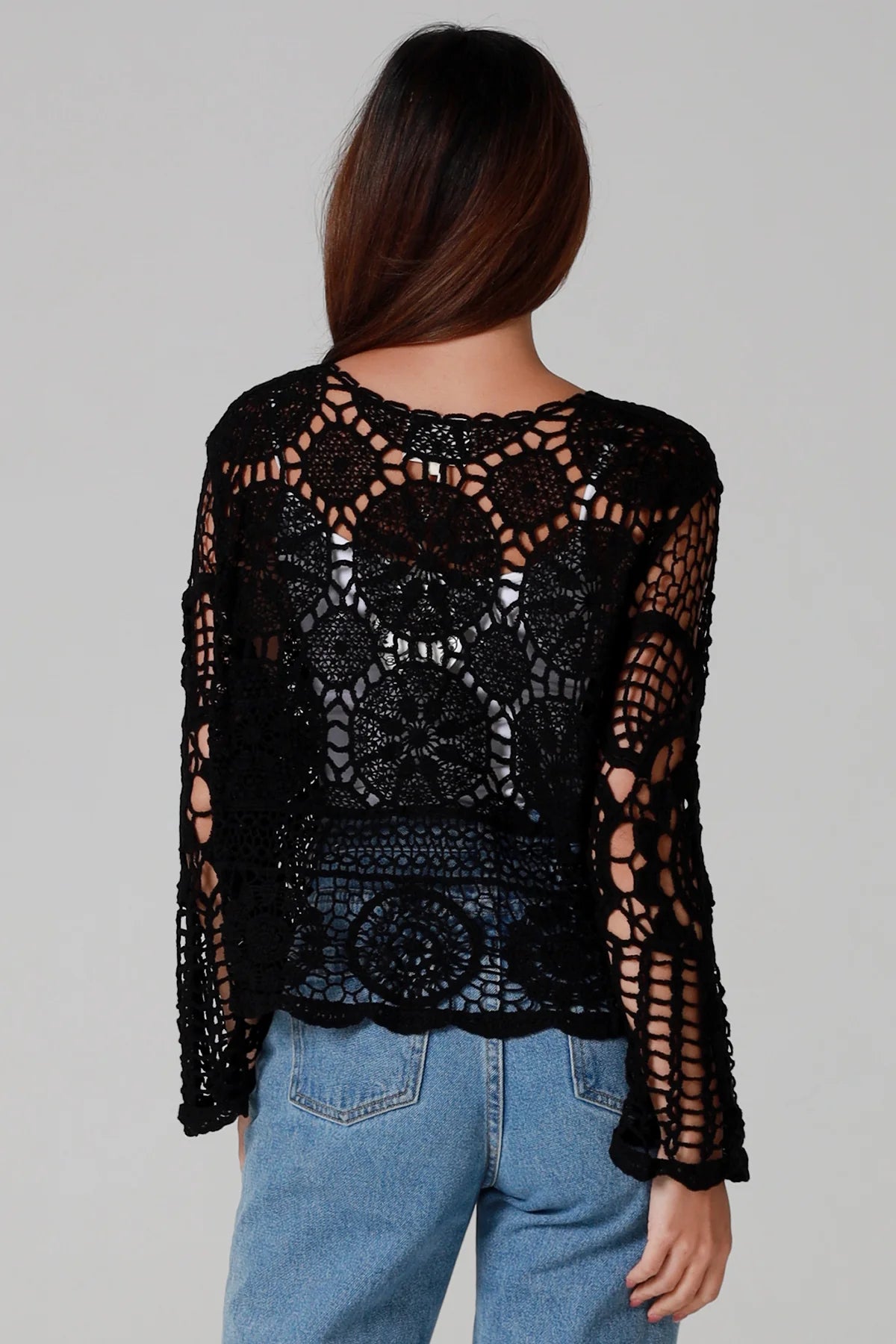 Woman in black 100% cotton crochet top with bell sleeves and tie front - one size boho top styled with denim