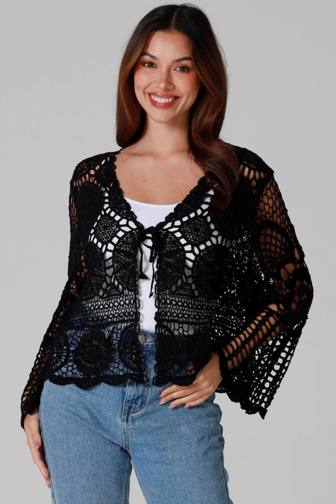 Woman in black 100% cotton crochet top with bell sleeves and tie front - one size boho top styled with denim