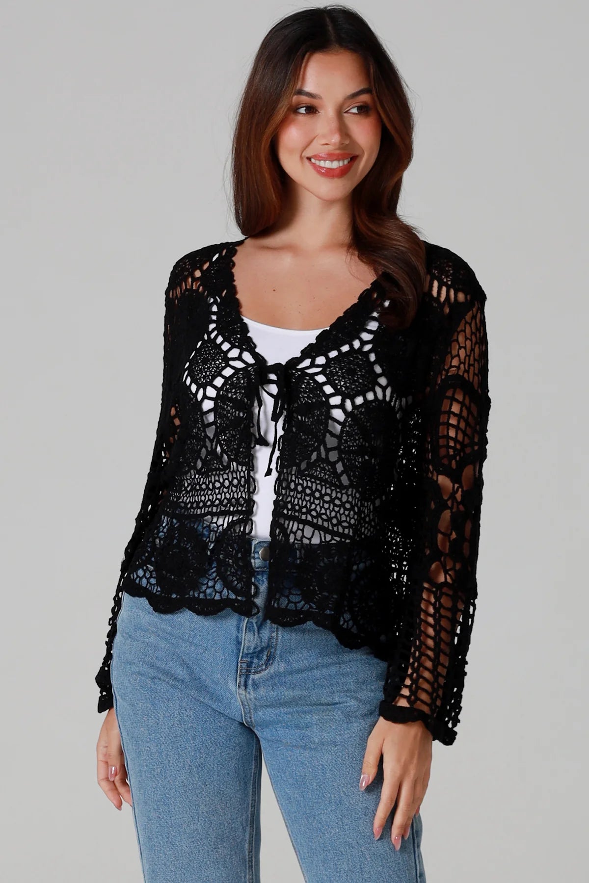 Woman in black 100% cotton crochet top with bell sleeves and tie front - one size boho top styled with denim