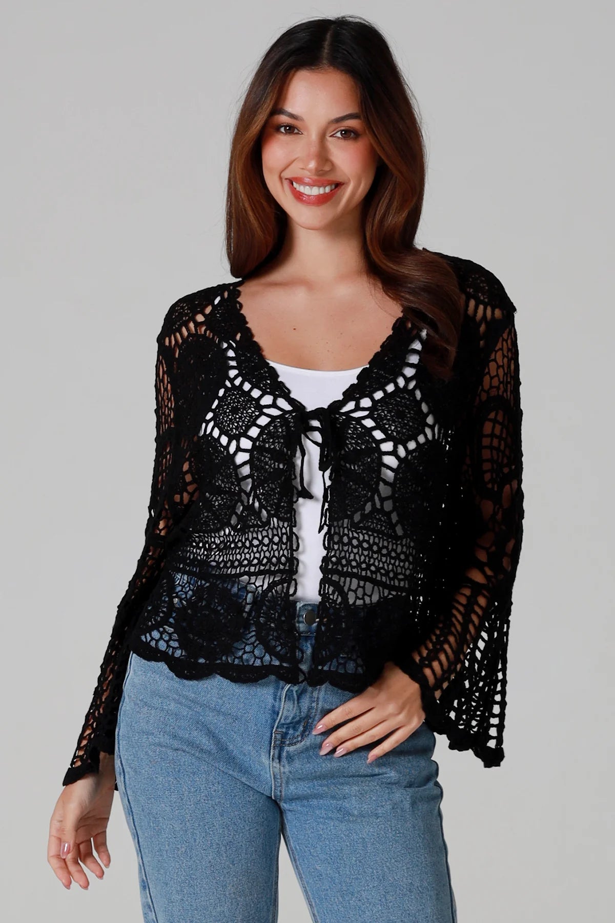 Woman in black 100% cotton crochet top with bell sleeves and tie front - one size boho top styled with denim