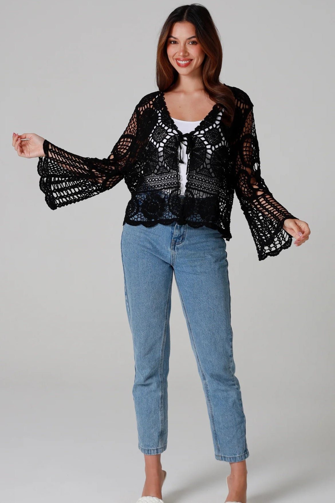 Woman in black 100% cotton crochet top with bell sleeves and tie front - one size boho top styled with denim