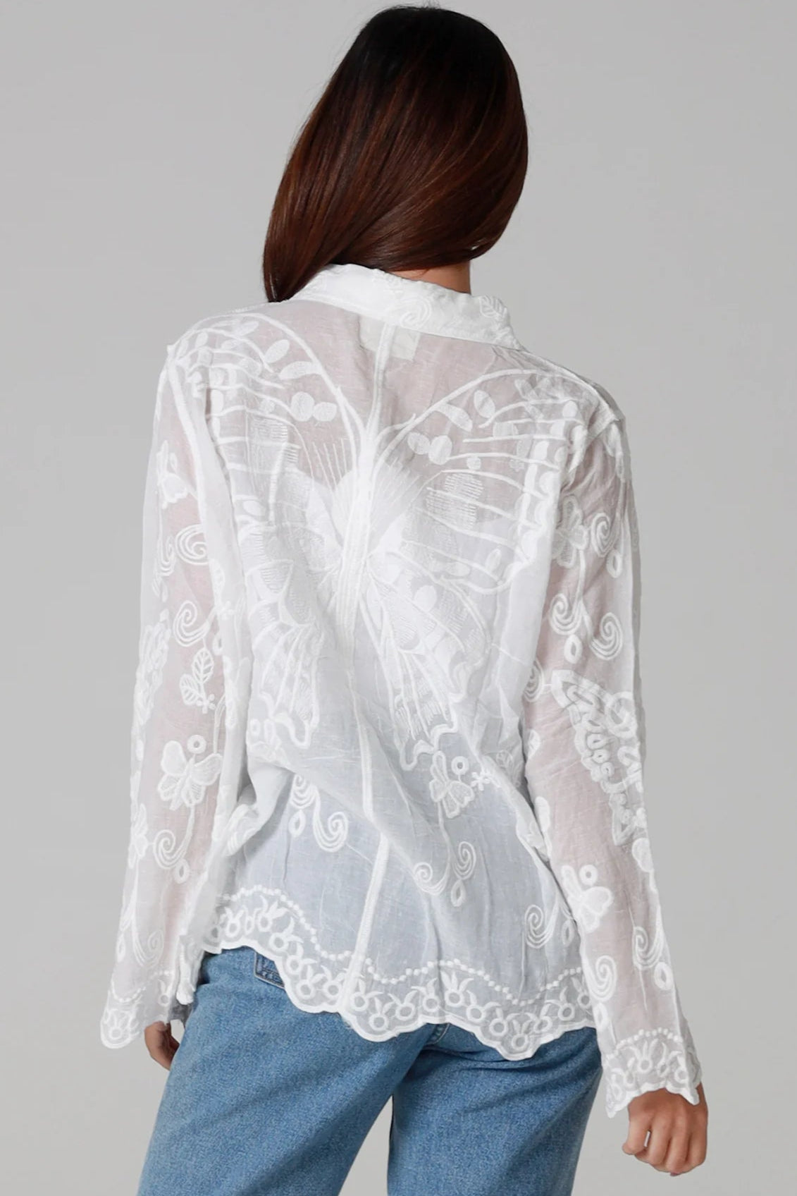 Woman in white cotton embroidered butterfly shirt with scalloped cuffs - boho blouse Australia.