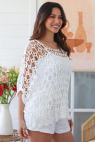 Woman wearing a white crochet cotton top with open-weave pattern, scalloped hem and batwing sleeves – Bohemian Love Runway