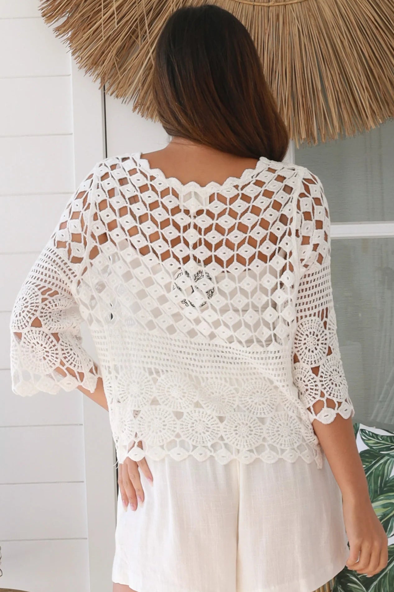 Woman wearing a white crochet cotton cardigan with diamond and floral pattern and scalloped sleeves - Boho Cardigan Australia
