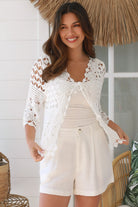 Woman wearing a white crochet cotton cardigan with diamond and floral pattern and scalloped sleeves - Boho Cardigan Australia