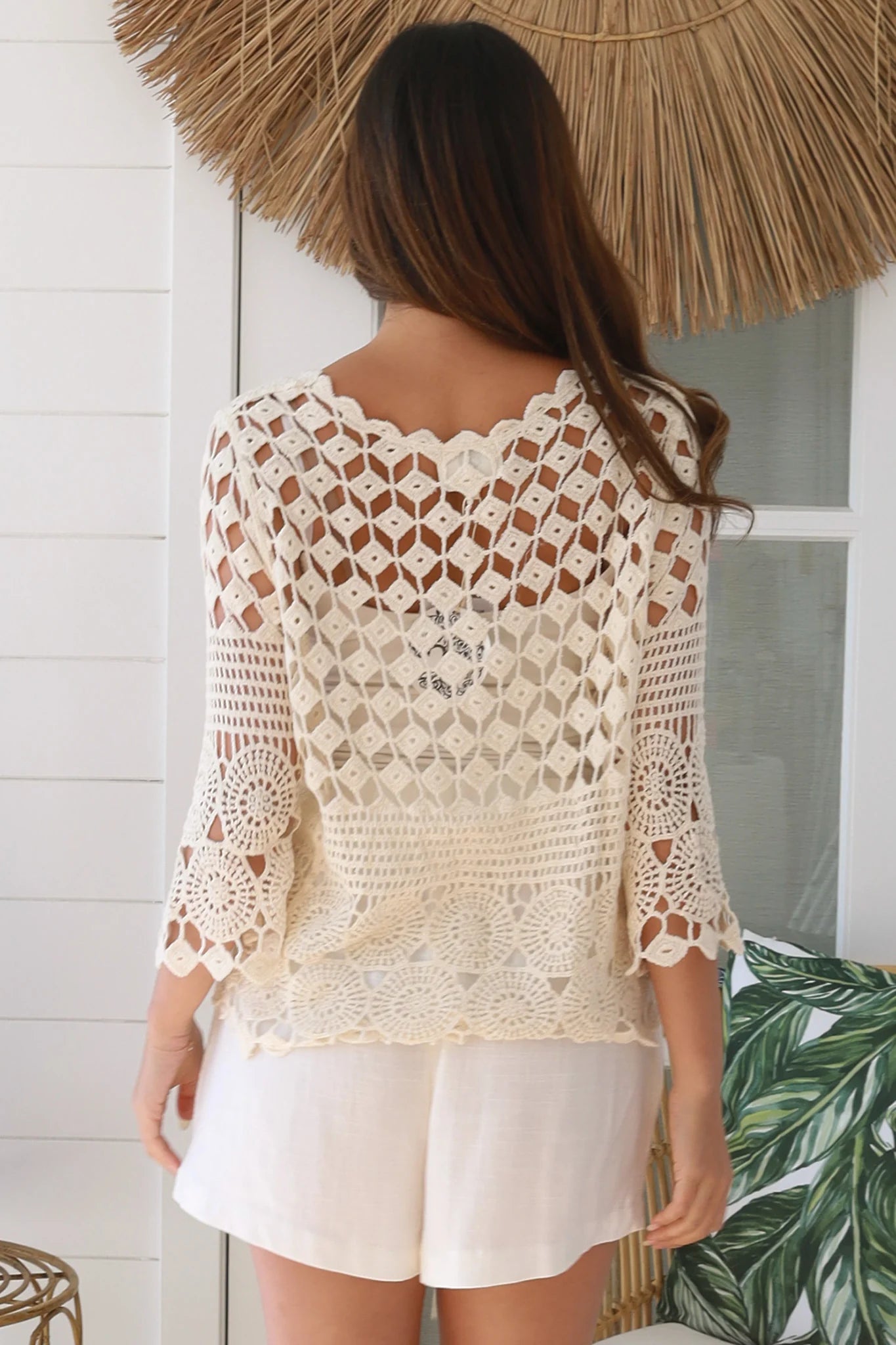 Woman wearing a cream crochet cotton cardigan with floral and diamond pattern and scalloped sleeves - boho fashion Australia