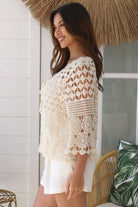 Woman wearing a cream crochet cotton cardigan with floral and diamond pattern and scalloped sleeves - boho fashion Australia