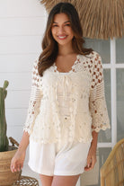 Woman wearing a cream crochet cotton cardigan with floral and diamond pattern and scalloped sleeves - boho fashion Australia