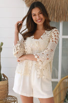 Woman wearing a cream crochet cotton cardigan with floral and diamond pattern and scalloped sleeves - boho fashion Australia