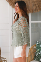 Woman wearing a sage green crochet cotton cardigan with floral and diamond pattern and scalloped sleeves - boho fashion Australia