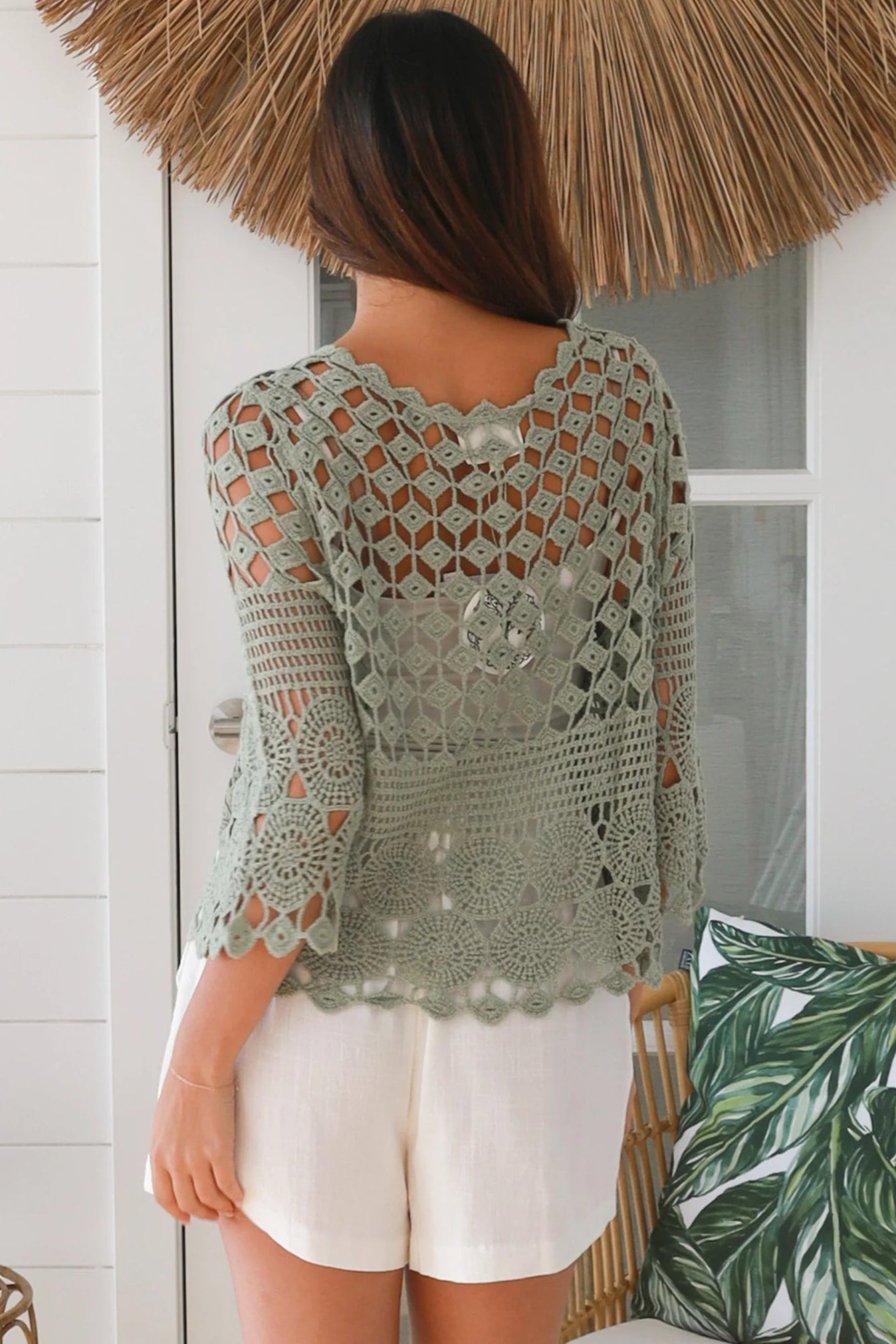 Woman wearing a sage green crochet cotton cardigan with floral and diamond pattern and scalloped sleeves - boho fashion Australia