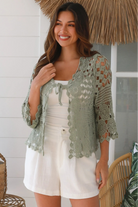 Woman wearing a sage green crochet cotton cardigan with floral and diamond pattern and scalloped sleeves - boho fashion Australia