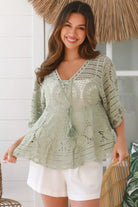 Woman in sage green cotton crochet top with embroidered floral lace and tassel ties - Olivia boho top Australia.