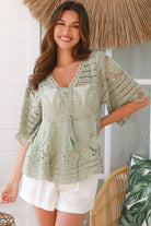 Woman in sage green cotton crochet top with embroidered floral lace and tassel ties - Olivia boho top Australia.
