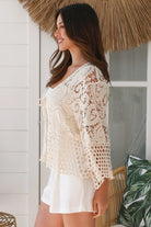 Woman wearing a cream crochet cotton jacket with bell sleeves and tie-front - boho layering piece Australia