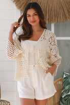 Woman wearing a cream crochet cotton jacket with bell sleeves and tie-front - boho layering piece Australia