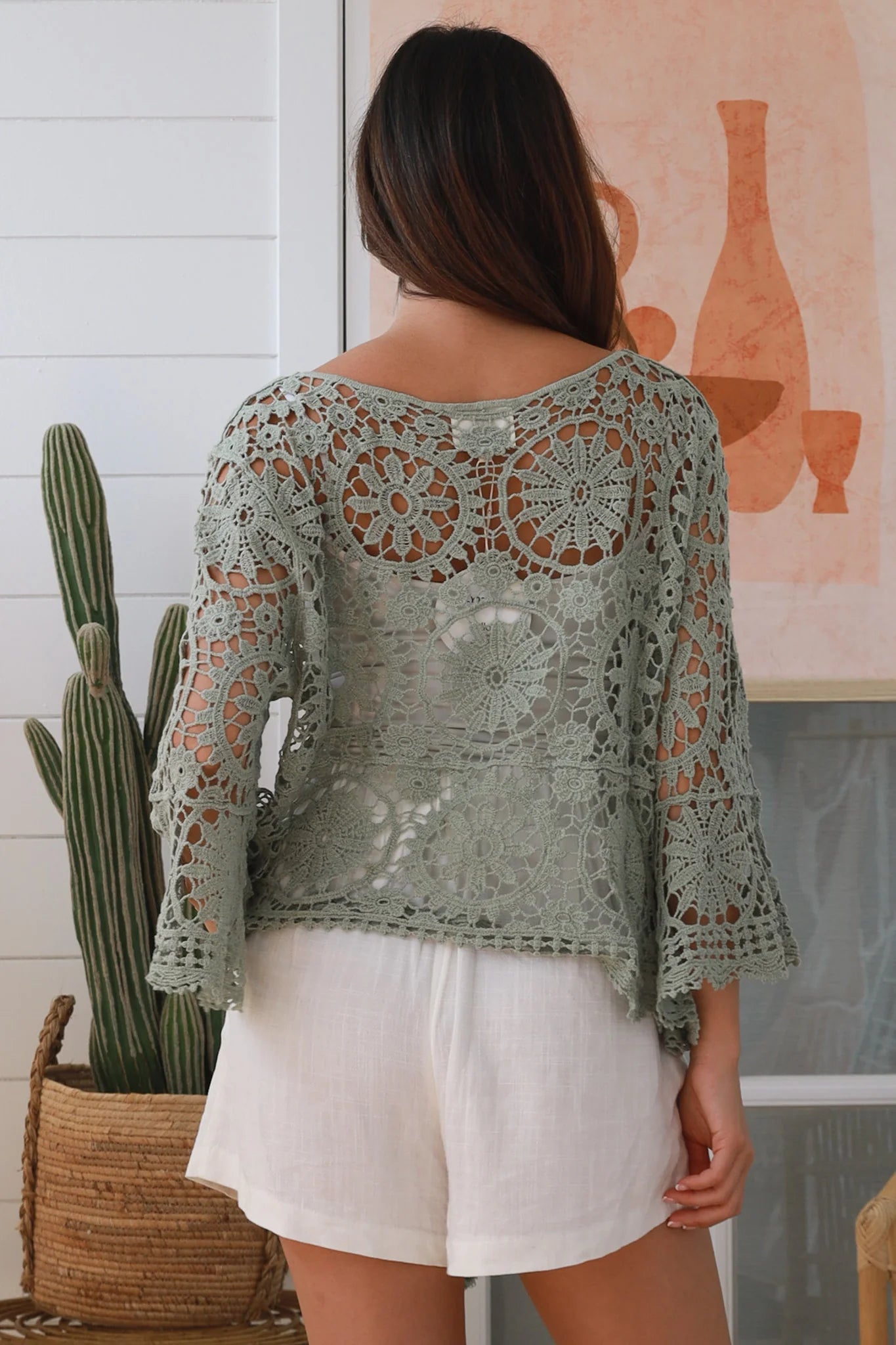 Woman wearing sage crochet boho top with dramatic bell sleeves - festival fashion Australia.