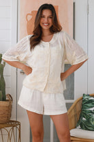 Woman wearing a cream embroidered cotton blouse with artisan trim – Zoe Embroidered Cotton Top Cream.