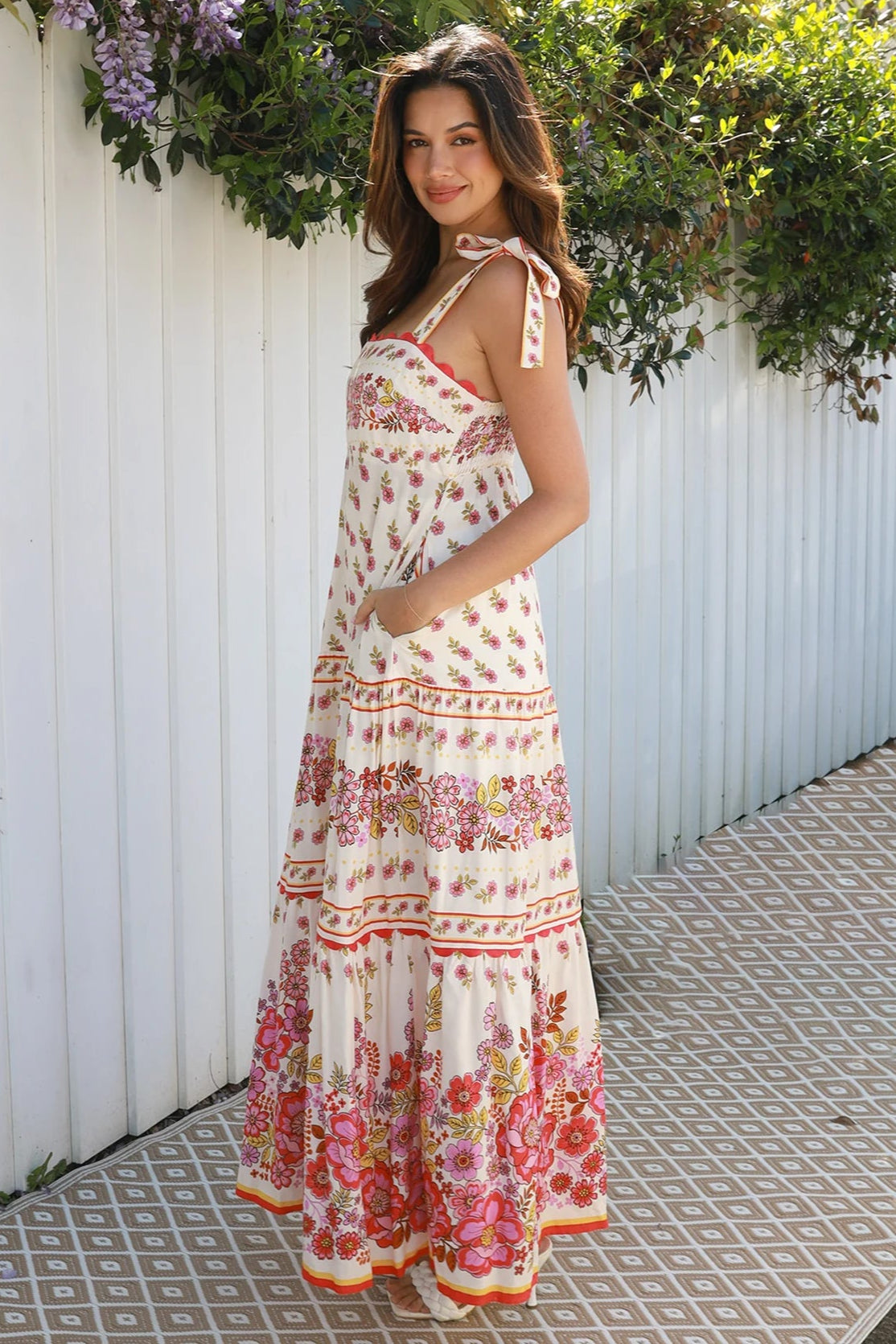 Cream rayon boho maxi dress with blush and rose floral print, tie shoulders, lace trim, and border hemline — Love at First Bloom