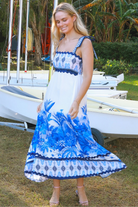 Model wearing blue-white Salty Palm maxi dress with tie straps and border print, light summer aesthetic for warm-weather days.