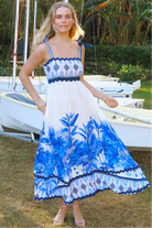 Model wearing blue-white Salty Palm maxi dress with tie straps and border print, light summer aesthetic for warm-weather days.