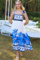 Model wearing blue-white Salty Palm maxi dress with tie straps and border print, light summer aesthetic for warm-weather days.