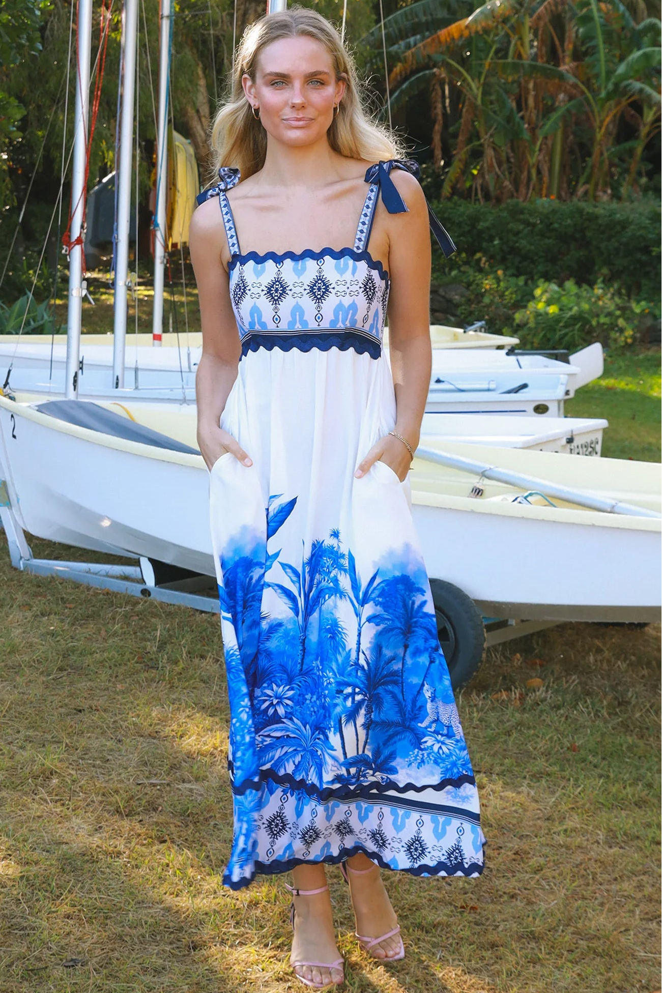 Model wearing blue-white Salty Palm maxi dress with tie straps and border print, light summer aesthetic for warm-weather days.