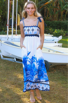 Model wearing blue-white Salty Palm maxi dress with tie straps and border print, light summer aesthetic for warm-weather days.