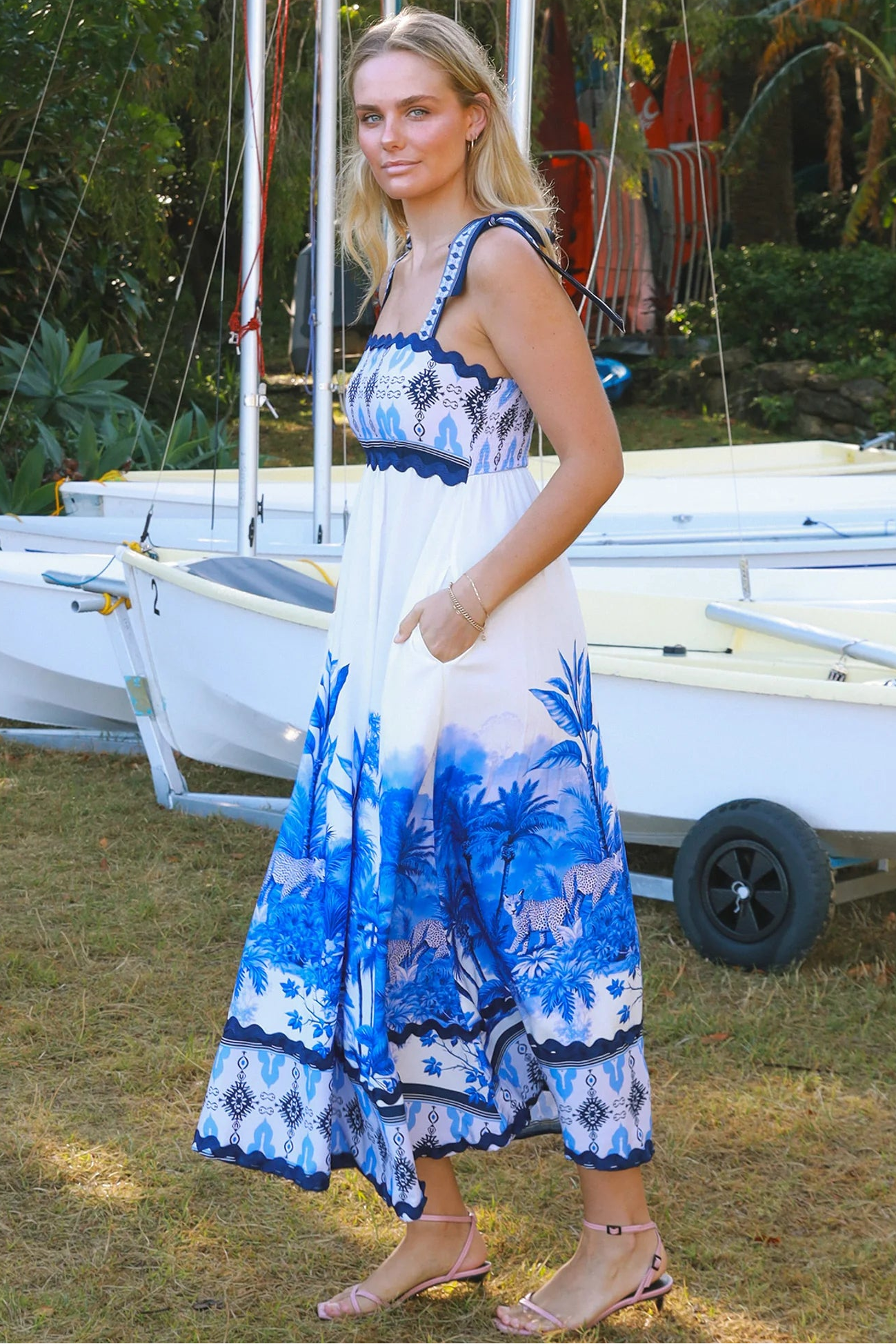 Model wearing blue-white Salty Palm maxi dress with tie straps and border print, light summer aesthetic for warm-weather days.