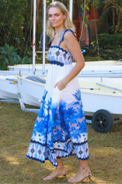 Model wearing blue-white Salty Palm maxi dress with tie straps and border print, light summer aesthetic for warm-weather days.