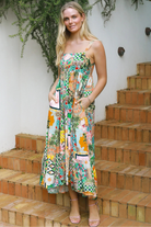 Woman in colourful ankle-sweeping island-print boho maxi dress with frill hemline and adjustable straps in bright summer.