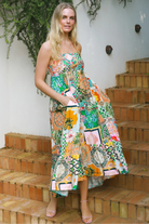 Woman in colourful ankle-sweeping island-print boho maxi dress with frill hemline and adjustable straps in bright summer.