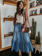 Woman in high-waisted tiered indigo cotton denim maxi skirt with button front - Bohemian Love Runway.