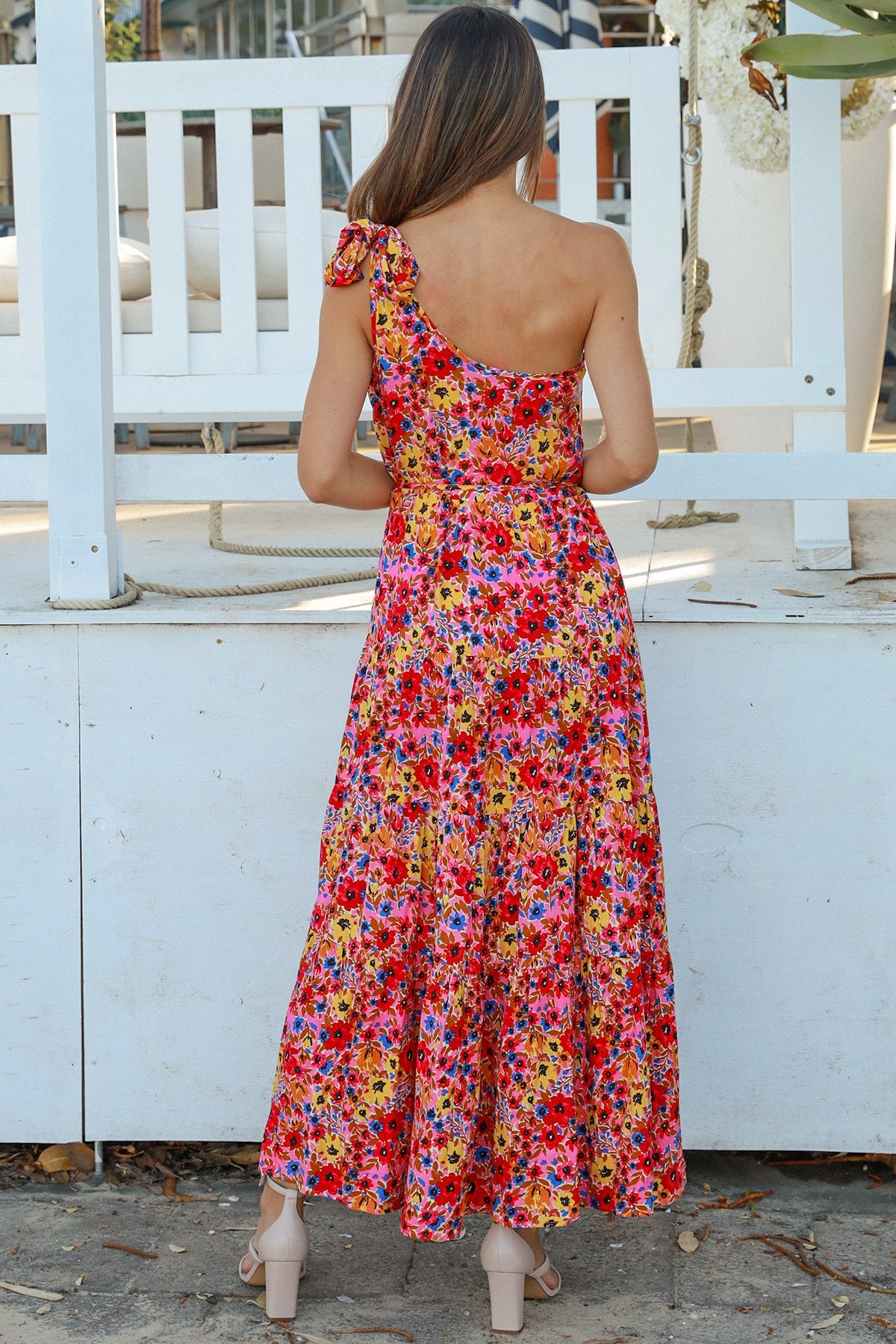 Women wearing a one-shoulder floral boho maxi dress with tassel waist tie - Lyric dress Australian summer fashion.