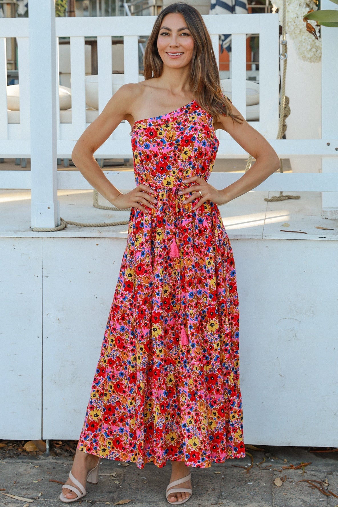 Women wearing a one-shoulder floral boho maxi dress with tassel waist tie - Lyric dress Australian summer fashion.