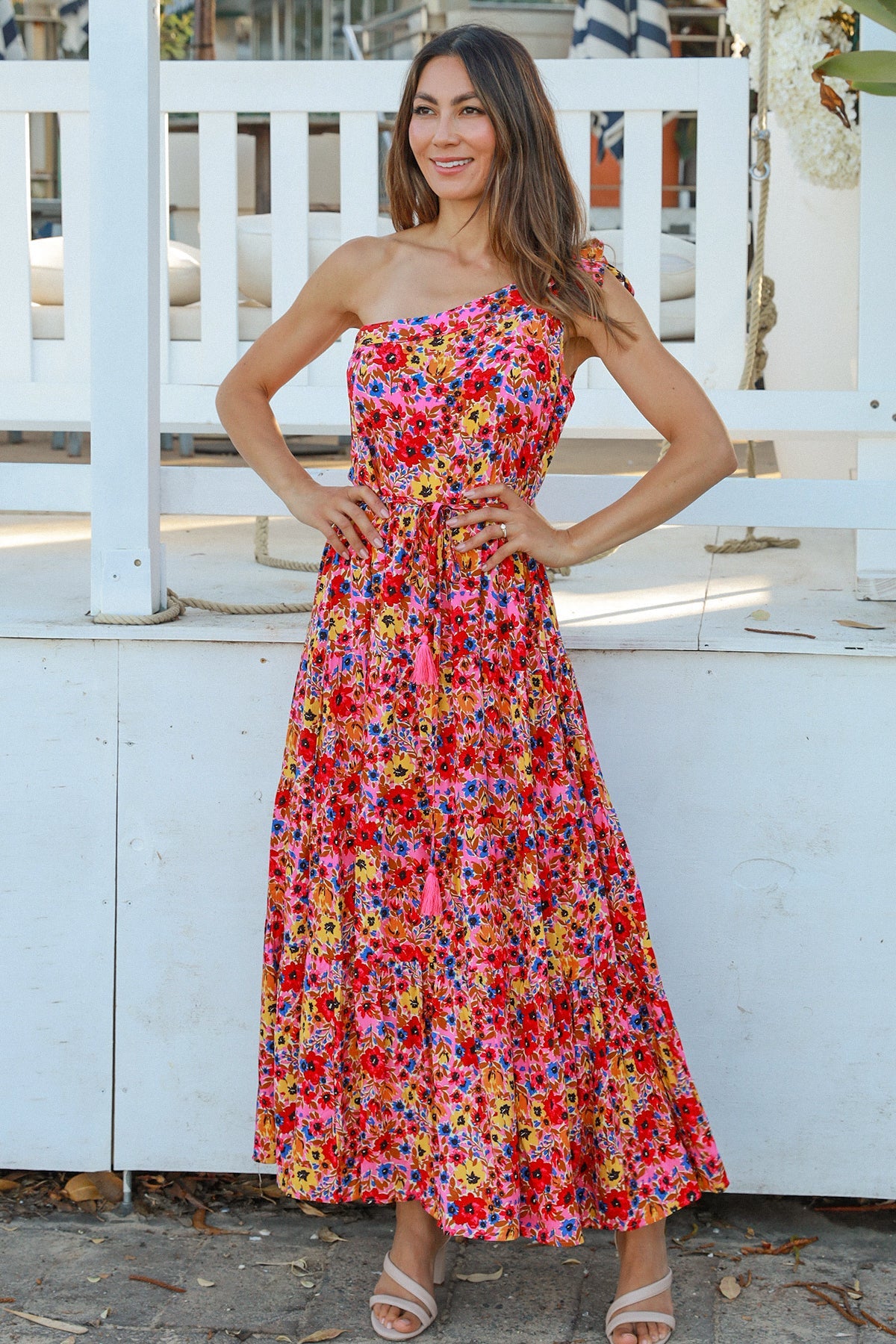 Women wearing a one-shoulder floral boho maxi dress with tassel waist tie - Lyric dress Australian summer fashion.