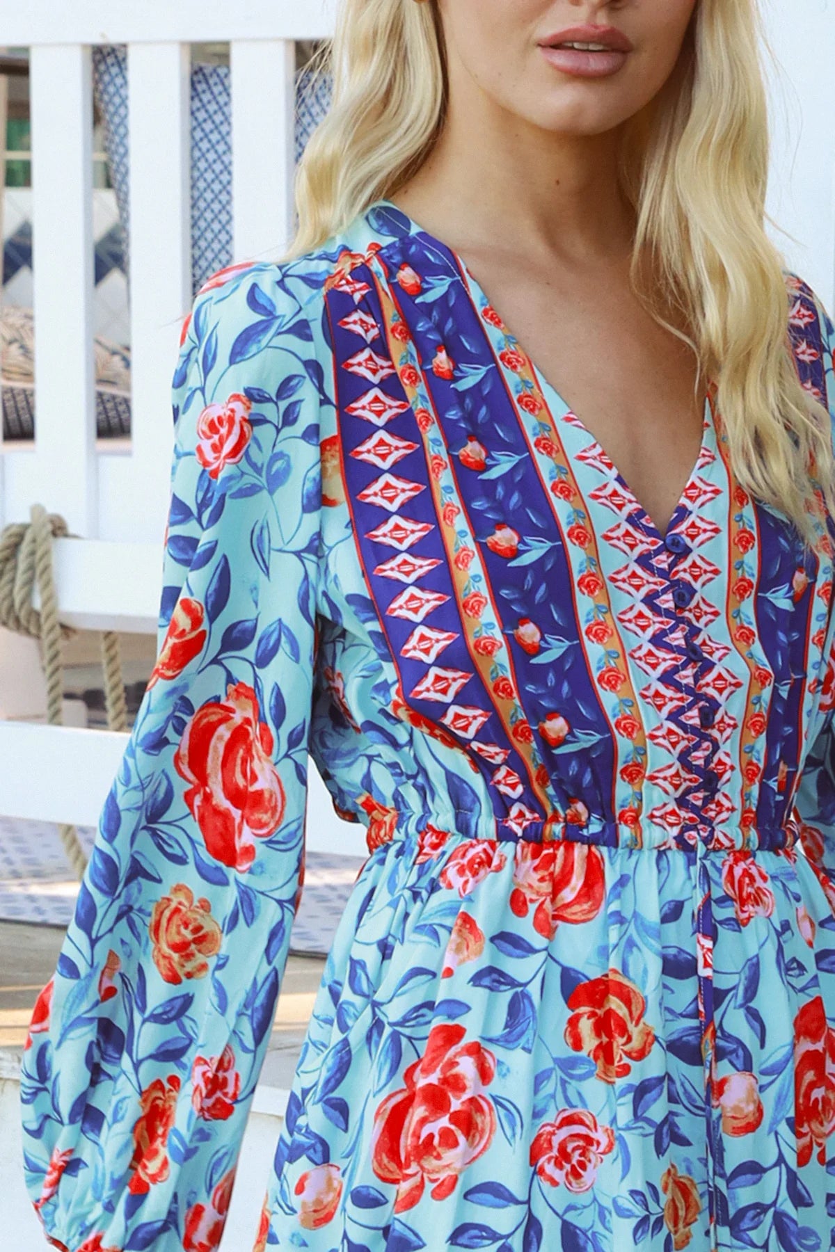 Blonde woman in blue floral boho mini dress with red roses and border print details - Clarice Rose Mini Dress Bohemian Love Runway.