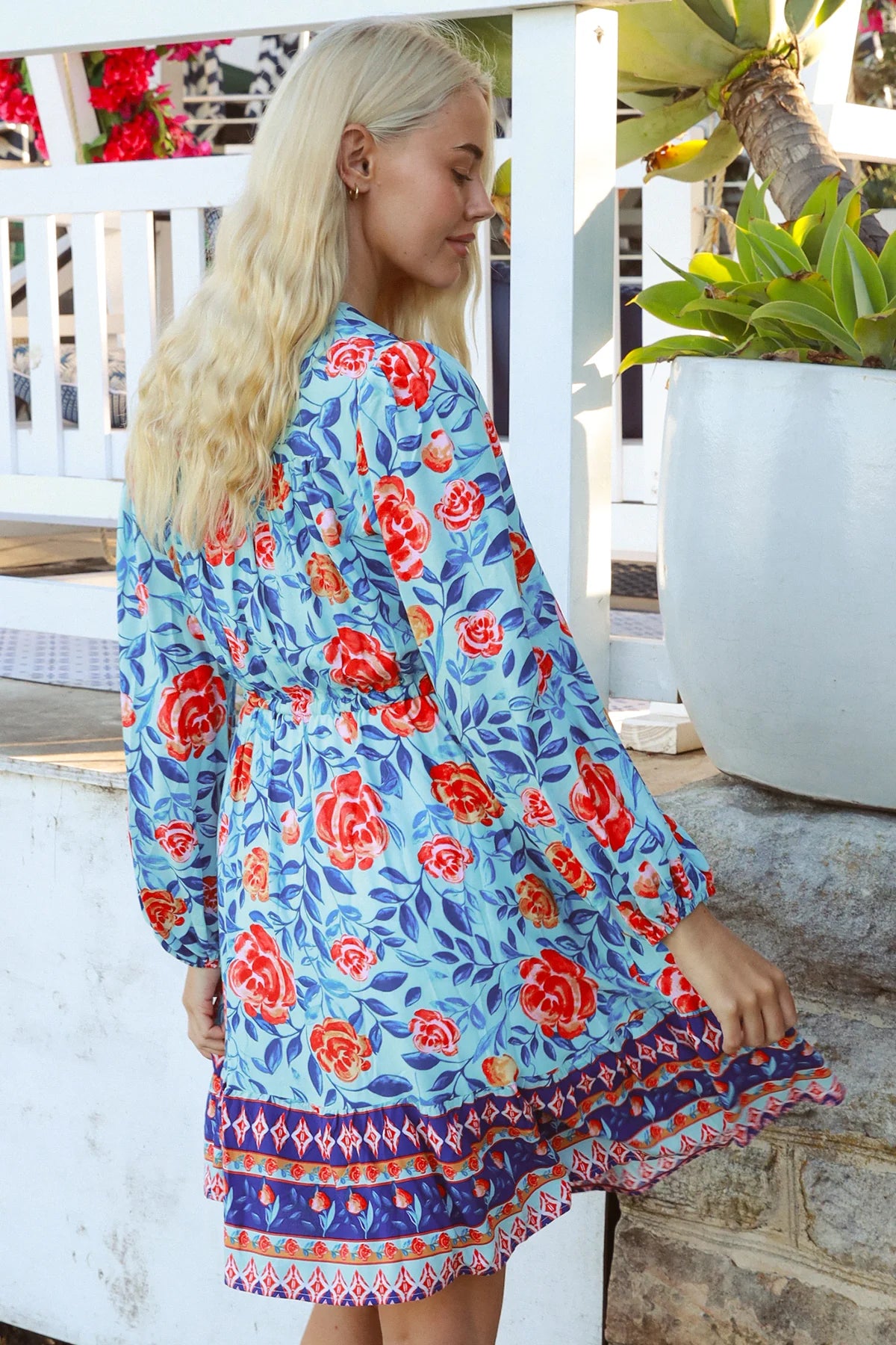 Blonde woman in blue floral boho mini dress with red roses and border print details - Clarice Rose Mini Dress Bohemian Love Runway.