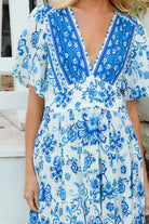 Woman in blue floral rayon bohemian midi dress with V-neckline flutter sleeves pockets and border frill hemline — Australia