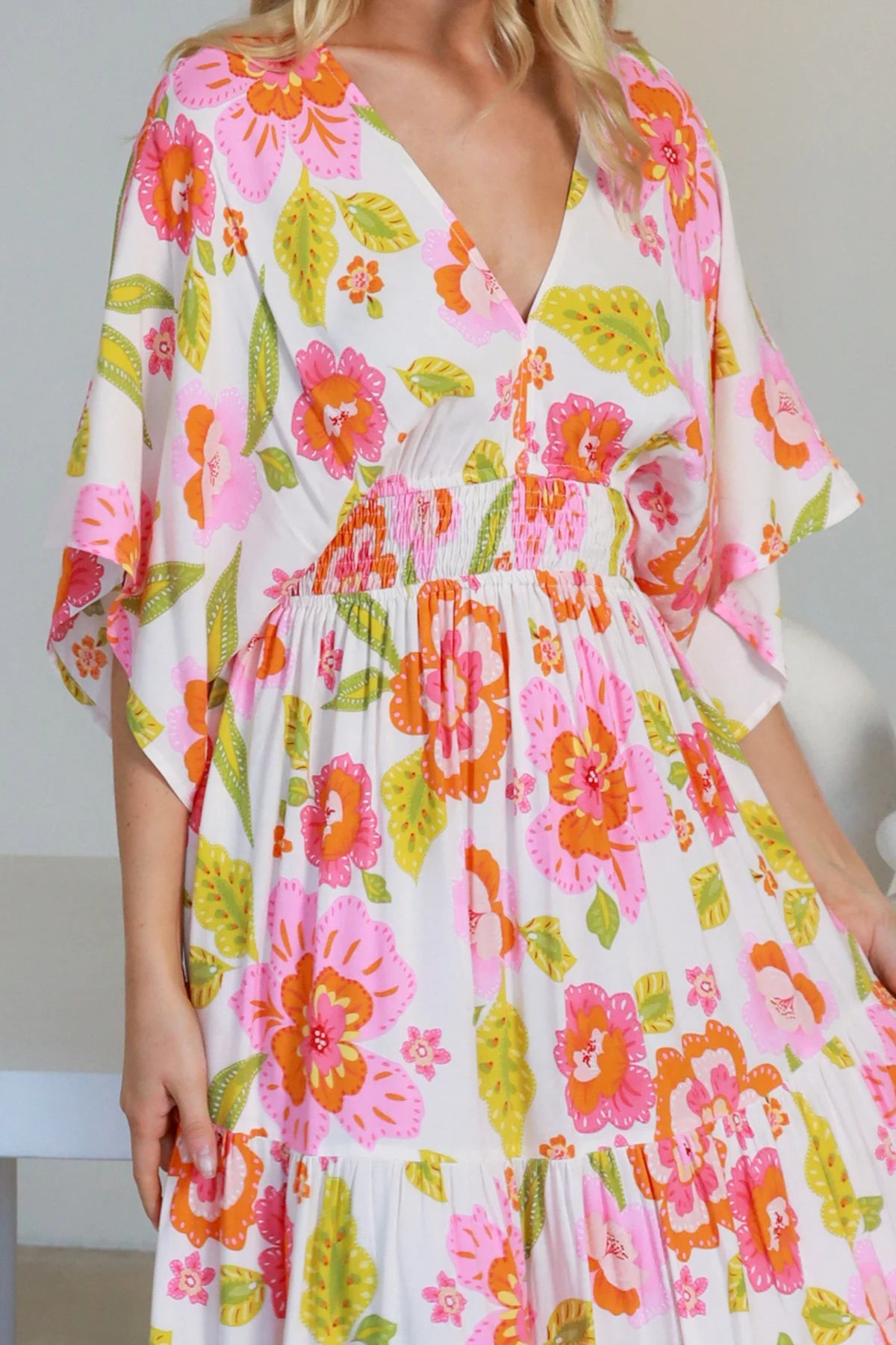 Woman in a coral-pink floral boho maxi dress with kimono sleeves - Isla Grace Tiered Maxi Dress Australia.